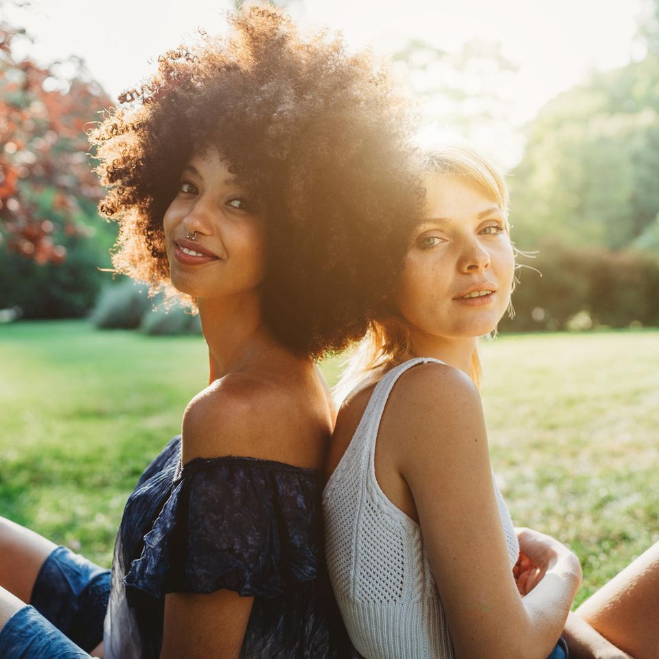 Zwei Freundinnen Rücken an Rücken: Warum es uns sogar guttut, uns mit anderen zu vergleichen