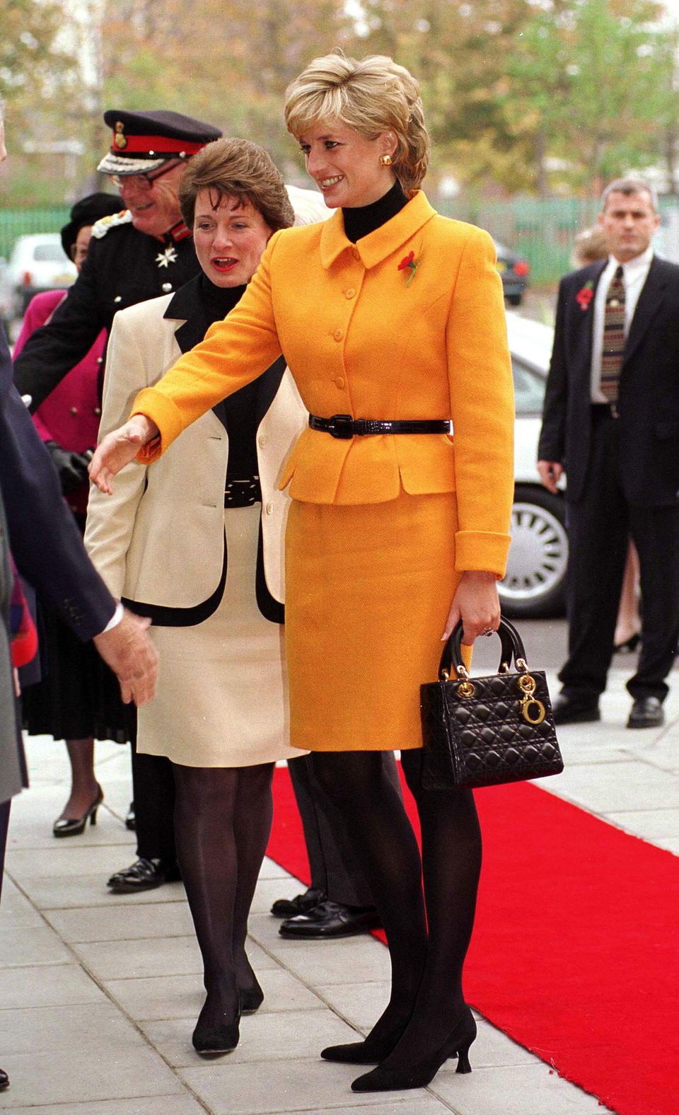 Prinzessin Diana im orangenen Anzug von Versace und mit ihrer geliebten Dior-Tasche in Liverpool, November 1995