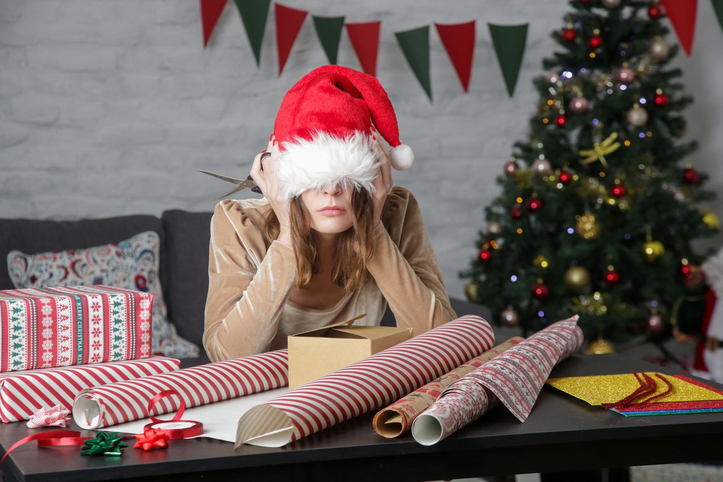 Eine Frau sitzt deprimiert vorm Weihnachtsgeschenkpapier