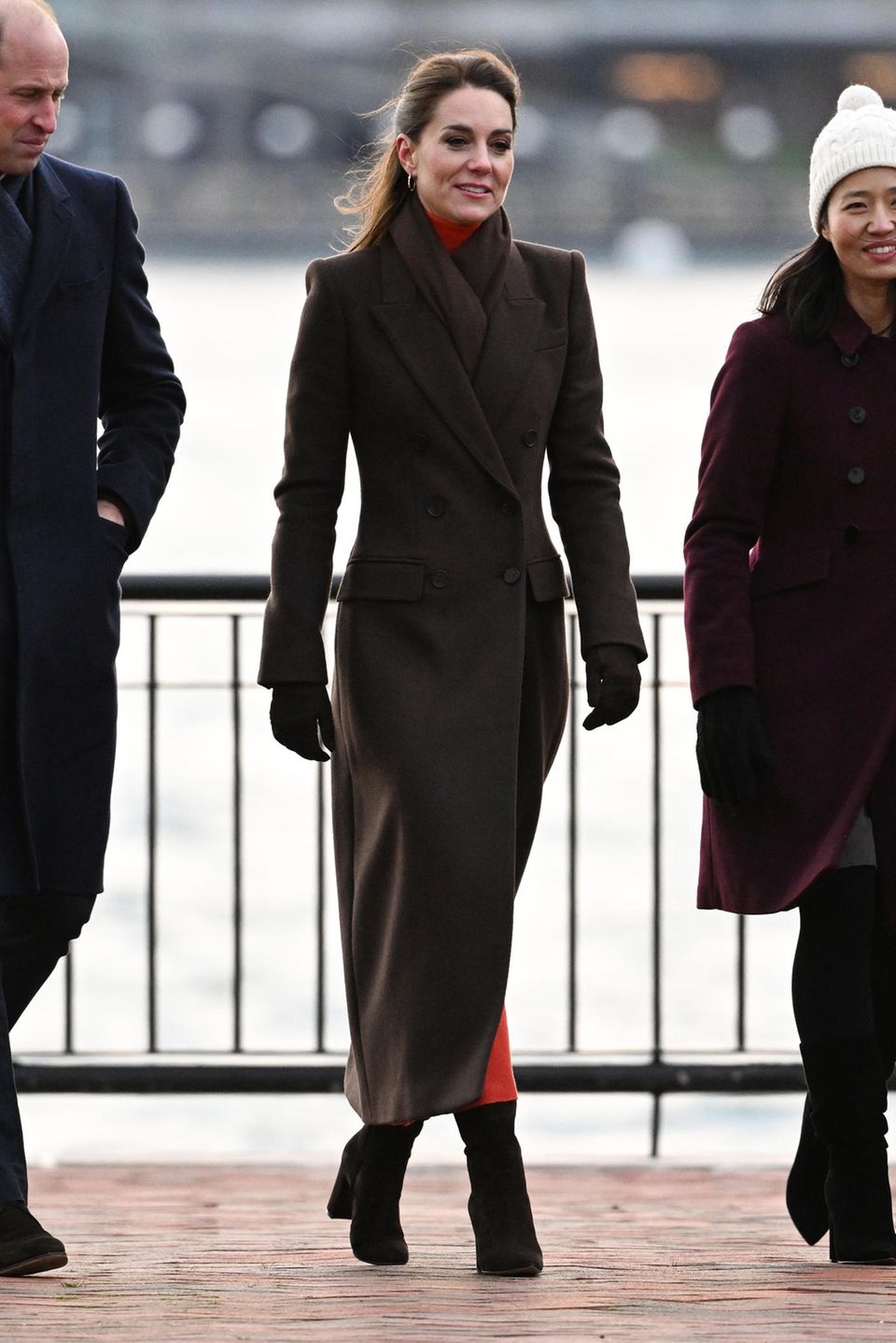 Gemeinsam mit William zeigt sich Kate in Boston in einem langen braunen Mantel im Military-Stil von Alexander McQueen – das selbe Modell mit doppelter Knopfleiste besitzt die Herzogin übrigens auch in rot. Schal, Handschuhe und Stiefel hält Kate im selben Farbton und schützt sich damit vor den winterlichen Temperaturen.
