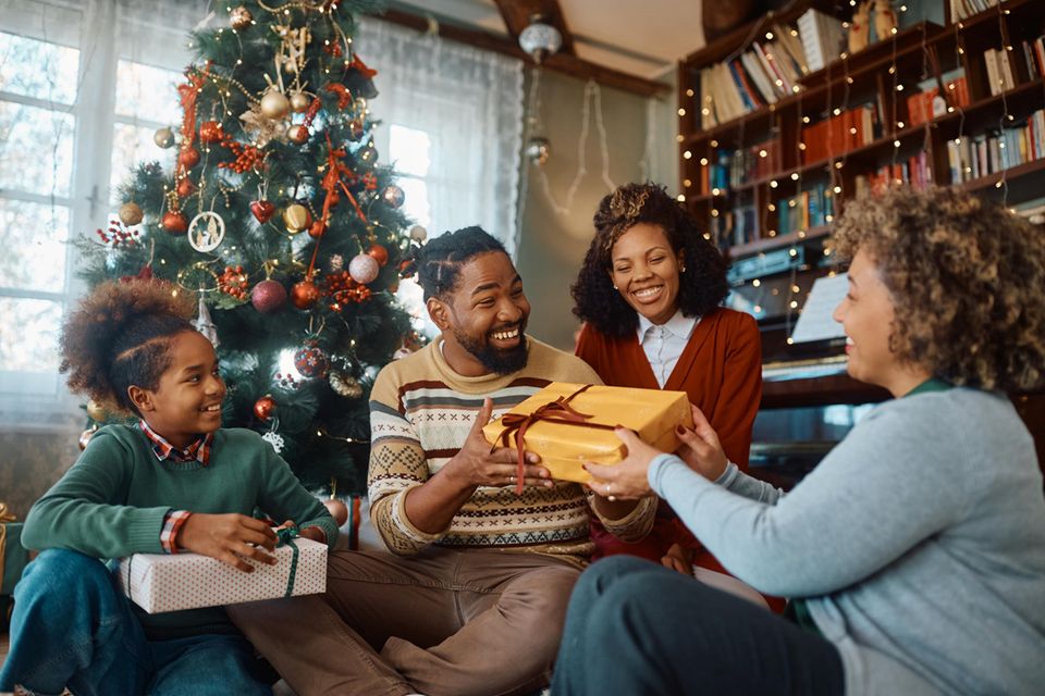 Familie, die unter dem Weihnachtsbaum Geschenke austauscht