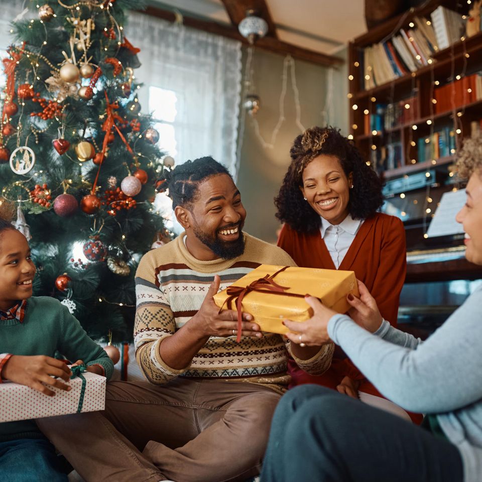 Familie, die unter dem Weihnachtsbaum Geschenke austauscht