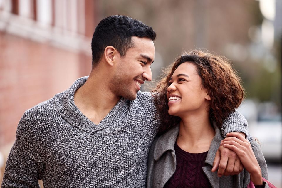 Liebesstrategie: Ein Paar läuft glücklich lachend über die Straße
