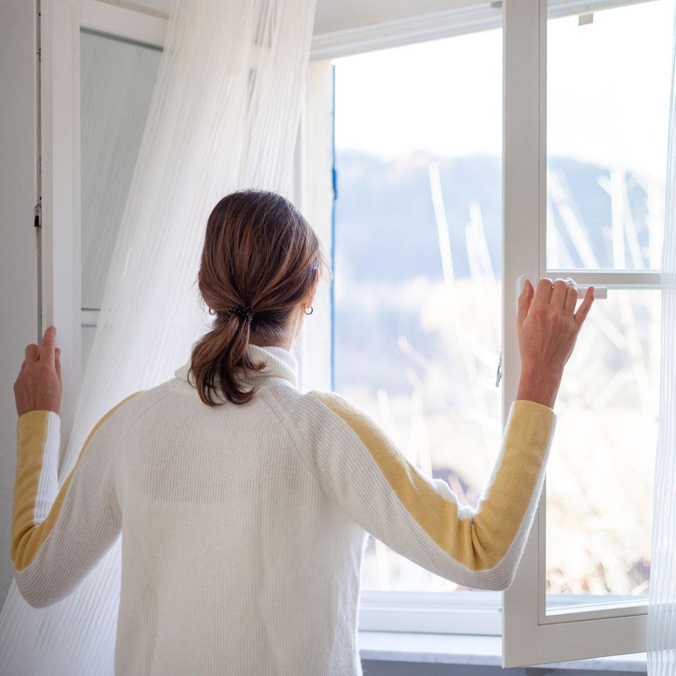 Frau macht das Fenster auf