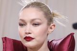 Gigi Hadids Make-up-Look ist einer der einprägsamsten der diesjährigen Met-Gala. Das Topmodel macht mit weinroten Vinyl-Lippen und frechem Space-Bun, in den sie ihre eisblonden Haare gedreht hat, auf sich aufmerksam. Was für ein Kontrast!