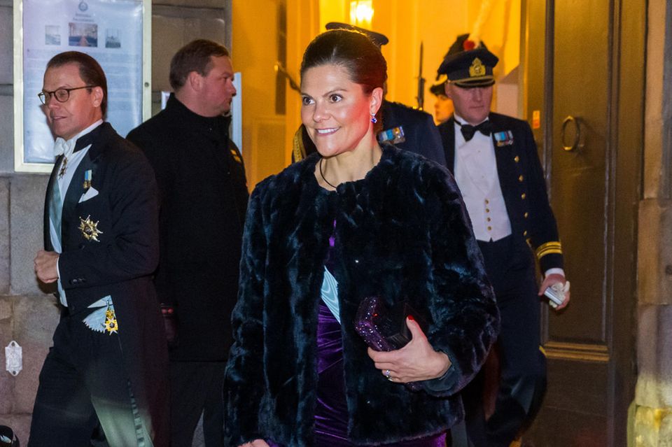 Prinzessin Victoria von Schweden wählt für ein Treffen mit der Akademie in Stockholm eine prunkvolle Samtrobe von Camilla Thulin. Dabei macht der weiche Stoff in Kombination mit der funkelnden Clutch und den silbernen Schuhen schon richtig Lust auf die Festtage. Um sich vor der kühlen Winterluft zu schützen, wählt die schwedische Prinzessin einen Kunstpelzmantel von Filippa K. Ein stylisches Outfit bei Kälte? Den Dreh hat sie definitiv raus.