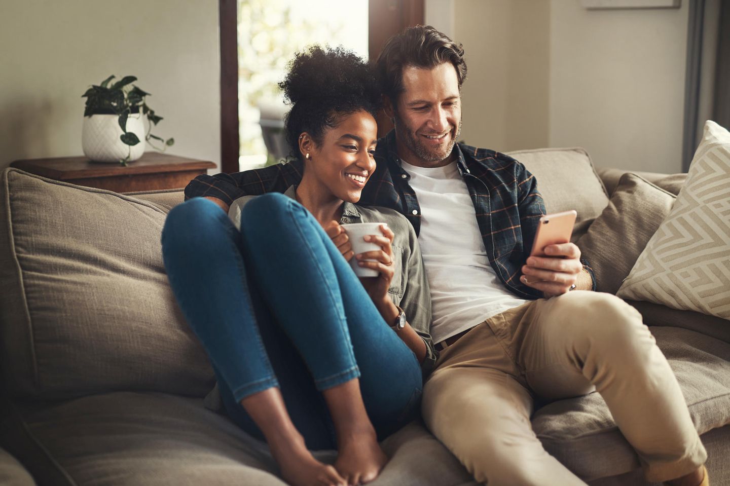 Horoskop: Mann und Frau lachend auf dem Sofa