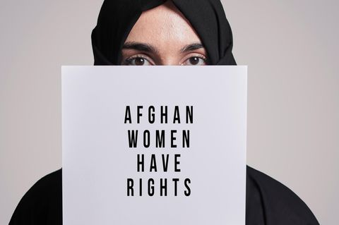 Eine afghanische Frau hält ein Schild hoch für mehr Rechte