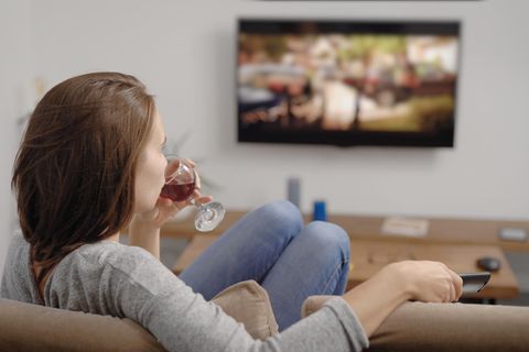 Frau mit Wein vor dem Fernseher: Diese Alltagsfehler sorgen klammheimlich dafür, dass du zunimmst