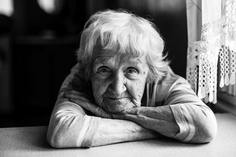 Eine ältere Frau schaut in die Kamera (schwarz-weißes Porträt)