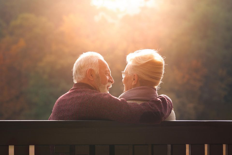 Ein älteres Paar sitzt zusammen auf einer Bank