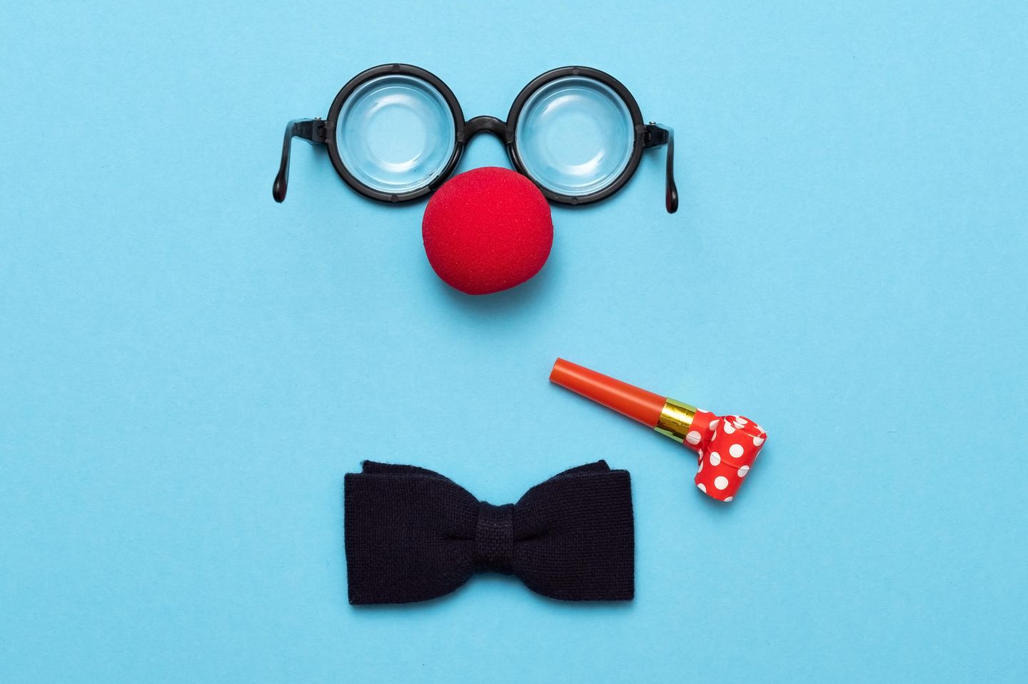 Clownworkshop: Clown Nase, Brille und Fliege liegen auf blauem Hintergrund