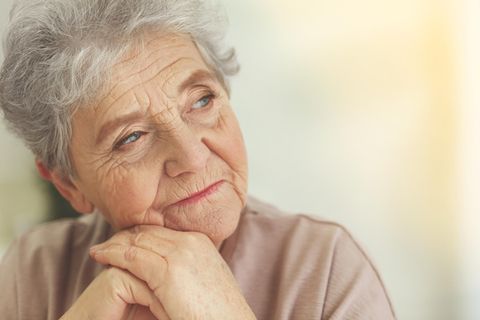 Eine ältere Frau schaut nachdenklich nach draußen