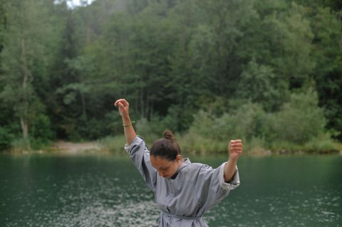 junge Frau tanzt in der Natur vor einem See