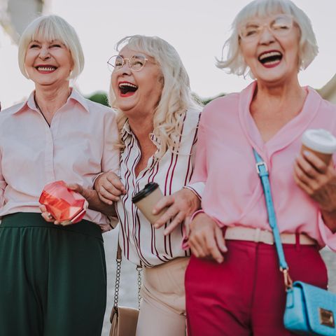 Drei ältere Frauen gehen lachend durch die Innenstadt