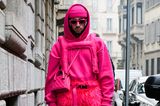 Barbiecore trifft Texturen. Ein Besucher der Fashion Week in Mailand kleidet sich von Kopf bis Fuß in Pink und setzt dabei auf Fell-, Leder- und Sweat. Besonders spannend: Auch seine Handschuhe sind in die Gute-Laune-Farbe getaucht. 