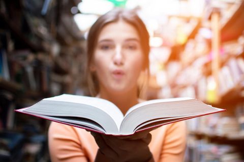 Lesen als Event: Eine junge Frau hält ein aufgeschlagenes Buch in der Hand