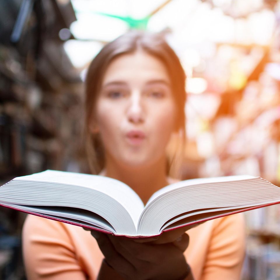 Lesen als Event: Eine junge Frau hält ein aufgeschlagenes Buch in der Hand