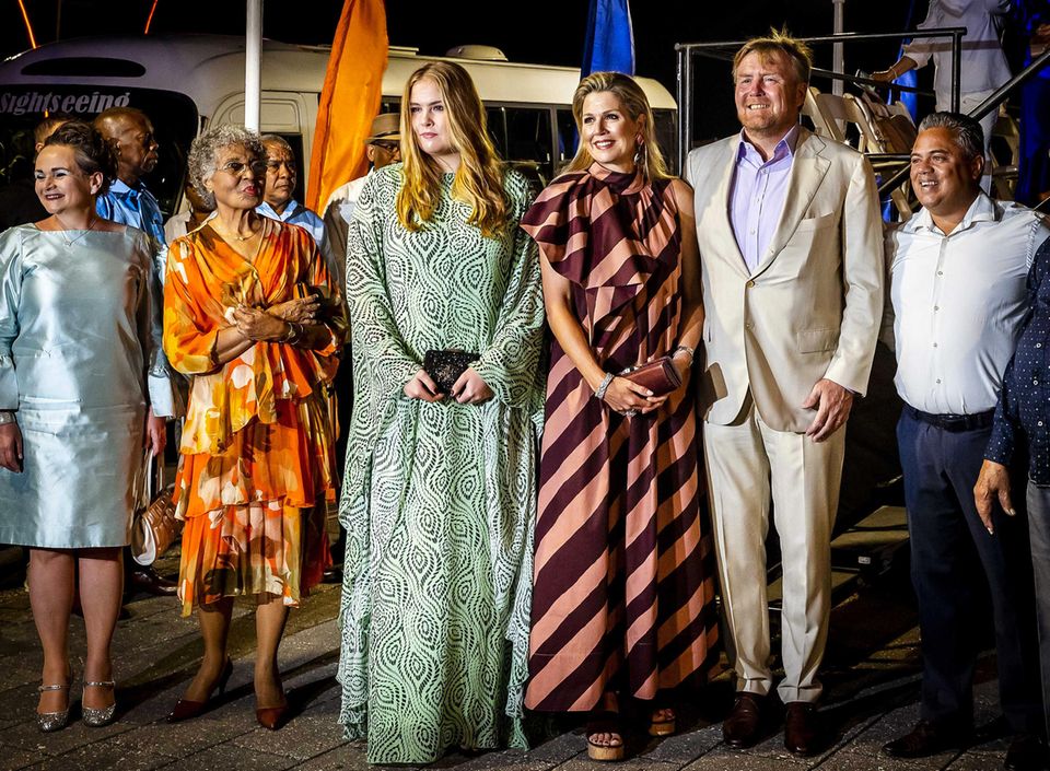 Die Kleider, die die royalen Damen dann abends beimJump-In Tumba Festival auf Curaçao tragen, sind ebenso tolle Hingucker, nicht zuletzt ihrer auffälligen Muster wegen. Die Königin bezaubert im schräggestreiften "Odia"-Kleid von Natan Couture, Amalia mag es im Kaftan-Look von Essentiel Antwerp etwas voluminöser.