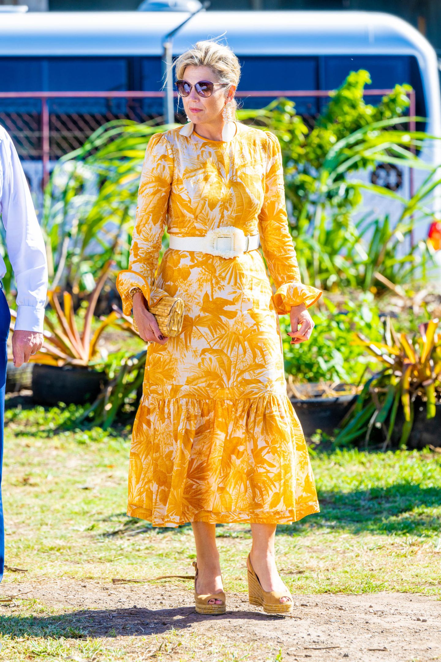Für den Besuch eines Naturschutzprojektes trägt Königin Máxima ein Kleid von Zimmermann mit floralem Print. Weiße Accessoires dienen als zusätzlicher Hingucker, dazu kombiniert sie eine Bambus Clutch und bequeme Wedges. 