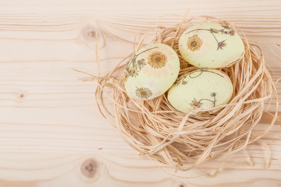 Eier färben: Gelbe Eier mit getrockneten Blumen beklebt