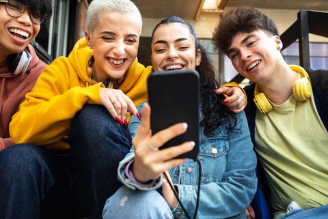 Jugendliche schauen lachend aufs Smartphone