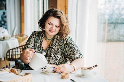 Frau trinkt genussvoll Kaffee und isst Kuchen: Selbstoptimierung zur Fastenzeit