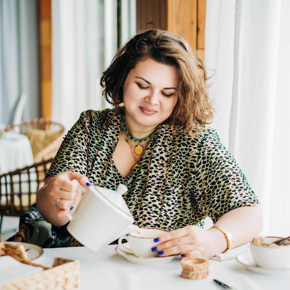 Frau trinkt genussvoll Kaffee und isst Kuchen: Selbstoptimierung zur Fastenzeit