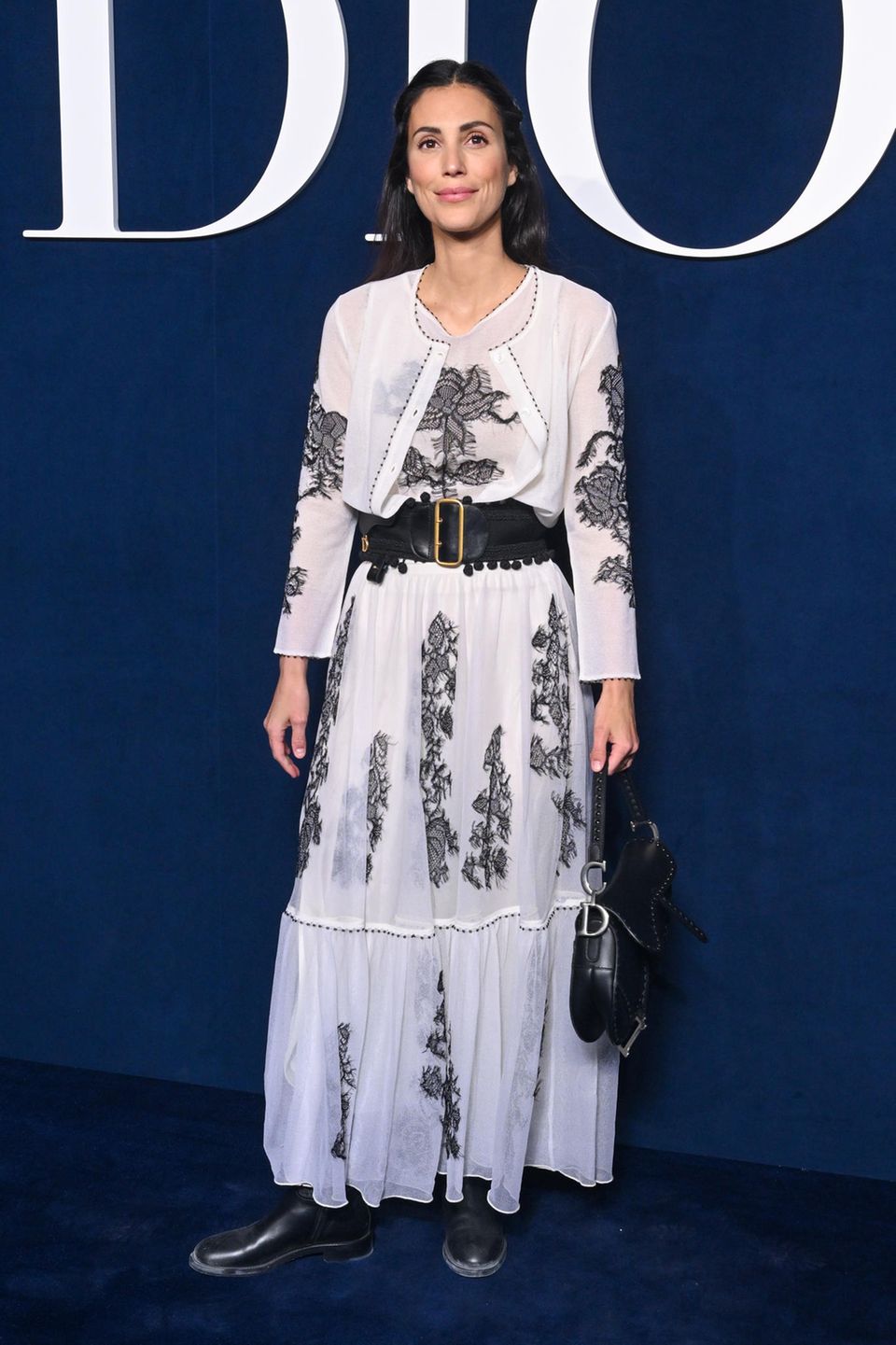 Zur Dior Herbst/Winter Show im Rahmen der Pariser Fashion Week erscheint Alessandra de Osma – natürlich – von Kopf bis Fuß in Dior. Besonders auffällig sind die gewählten Accessoires: Der Gürtel mit Gürteltasche und die schwarze Saddle-Bag geben dem Outfit einen lässigen Touch.