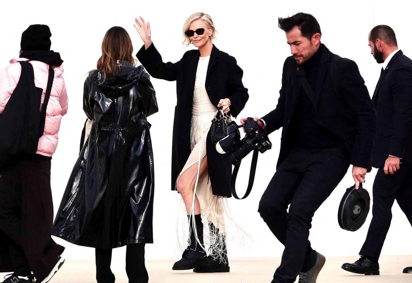 Wenn Hollywoodstar Charlize Theron kommt, rennen die Fotograf:innen, um das beste Foto zu schießen. Sie bleibt auf dem Weg zu ihrem Platz in der Front Row von Dior ganz entspannt.