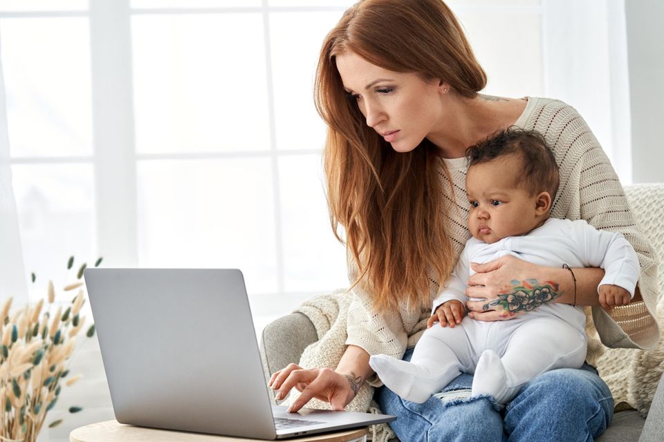 Macherinnen: Eine junge Frau sitzt mit einem Baby auf dem Schoß vor dem Laptop