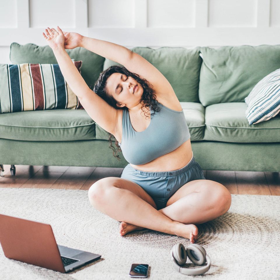 Frau dehnt sich auf dem Fußboden: 6 gute Gründe, das Workout heute ausfallen zu lassen