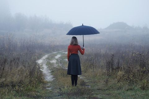 Frau steht im Regen: Diese selbstzerstörerischen Denkmuster sollten wir uns abgewöhnen