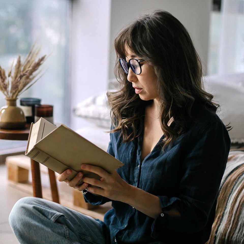 Frau liest gespannt ein Buch: 5 Bücher, die dich zum Nachdenken anregen werden