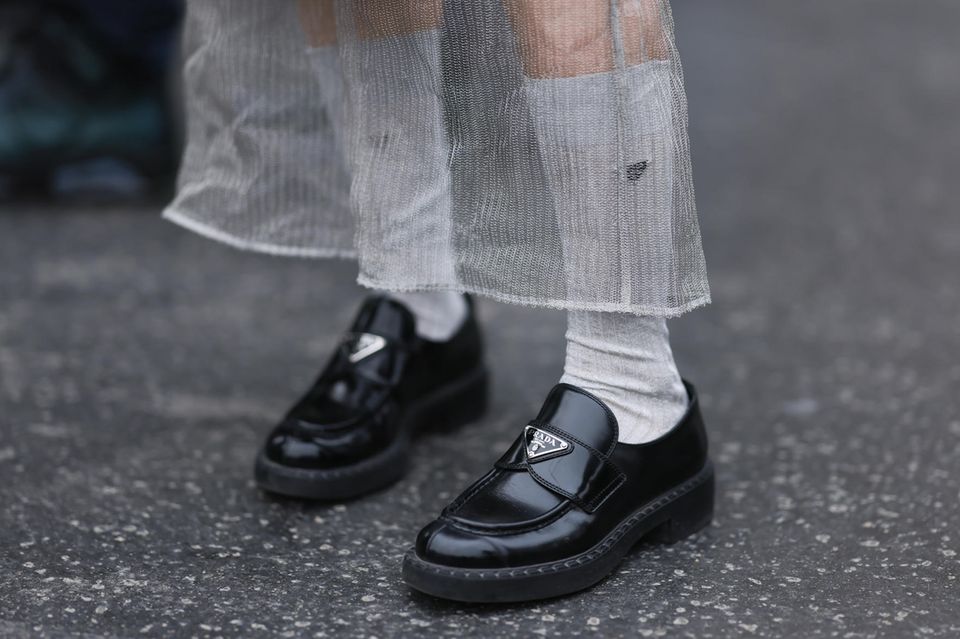 Die perfekten Loafer: Eine Frau trägt schwarze Lederloafer der Marke Prada.