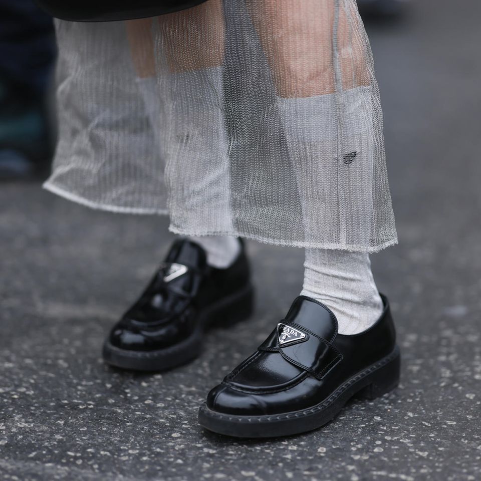 Die perfekten Loafer: Eine Frau trägt schwarze Lederloafer der Marke Prada.