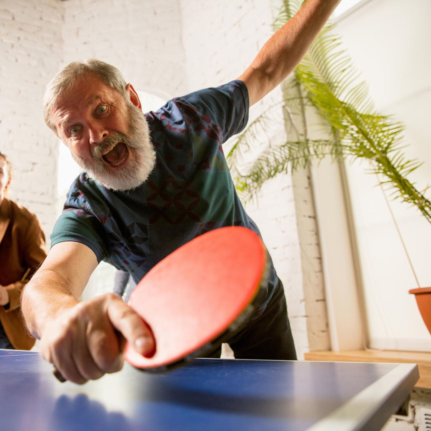 Ein älterer Herr spielt enthusiastisch Tischtennis