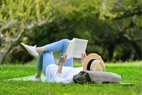 Eine Frau liegt auf einer Wiese und liest