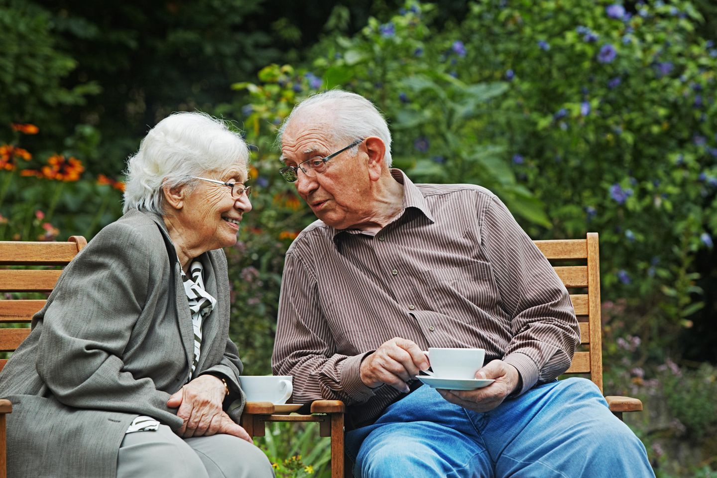 Ein älteres Ehepaar sitzt im Garten und trinkt Kaffee