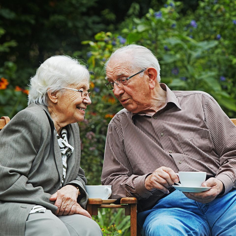 Ein älteres Ehepaar sitzt im Garten und trinkt Kaffee