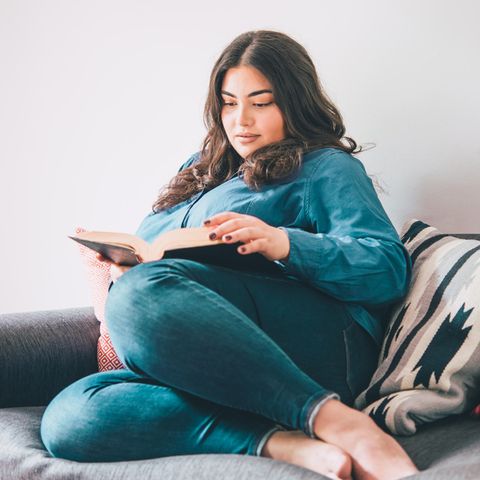 Frau liest auf der Couch ein Buch: Diese 5 Gewohnheiten haben intelligente Frauen