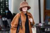 Unter einem Bucket-Hat im Leoparden-Stil trägt Sharon Osbourne ihre Shopping-Beute durch die Straßen von Los Angeles. Während ihre Kopfbedeckung ein modisches Statement ist, hält sie es mit ihrem restlichen Outfit schlichter. Zur Jeans mit ausgefranstem Saum, trägt sie einen schwarzen Pullover und einen braunen Mantel. 