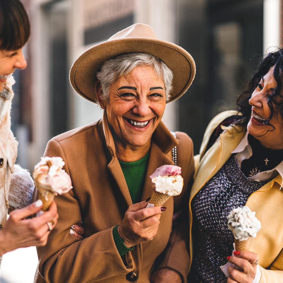 Drei ältere Frauen essen lachend Eis