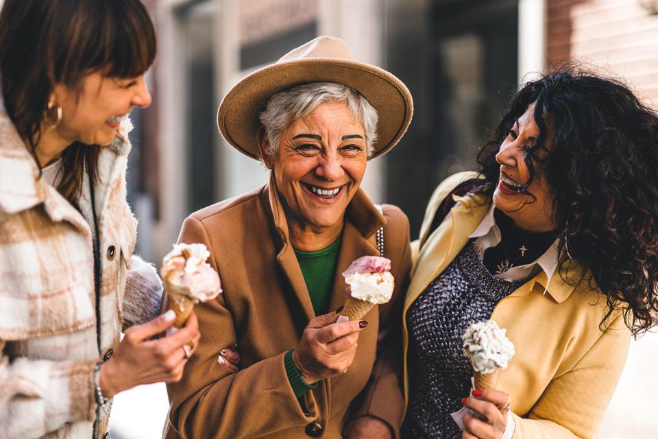 Drei ältere Frauen essen lachend Eis