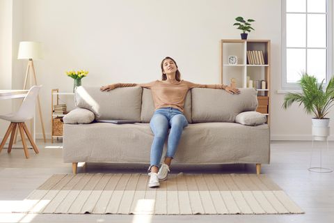 Zufriedene Frau im Wohnzimmer: 4 geniale Interior-Tipps, die keinen Cent kosten