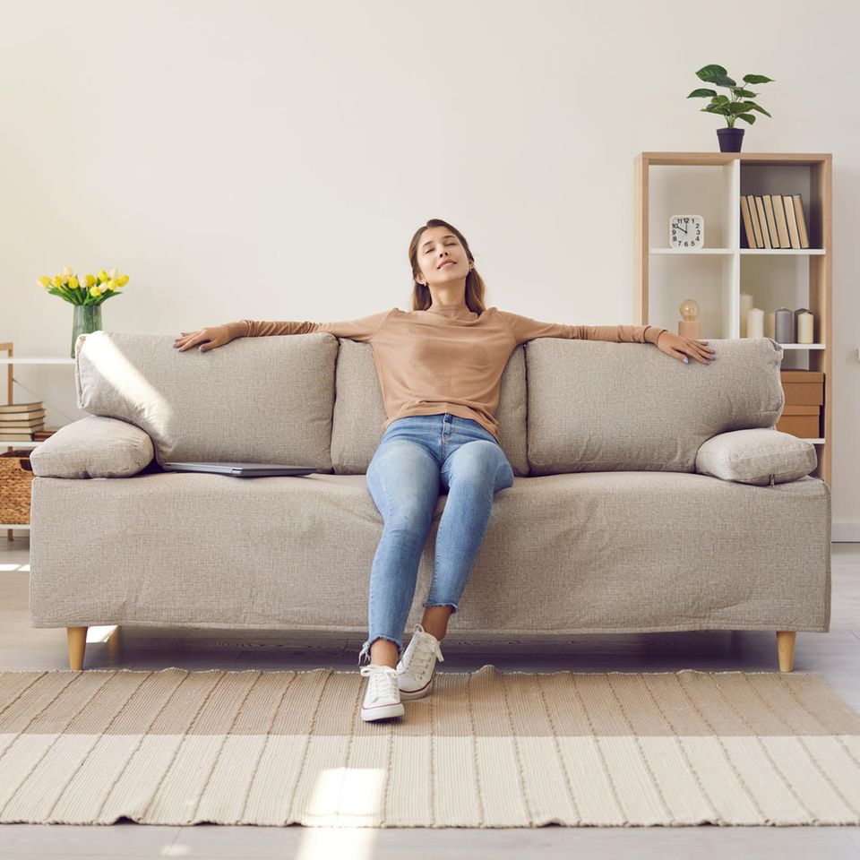 Zufriedene Frau im Wohnzimmer: 4 geniale Interior-Tipps, die keinen Cent kosten