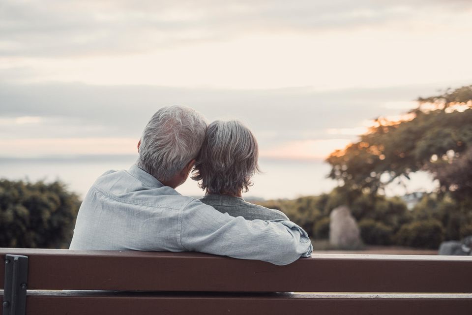 Ein älteres Paar sitzt auf einer Bank und umarmt sich