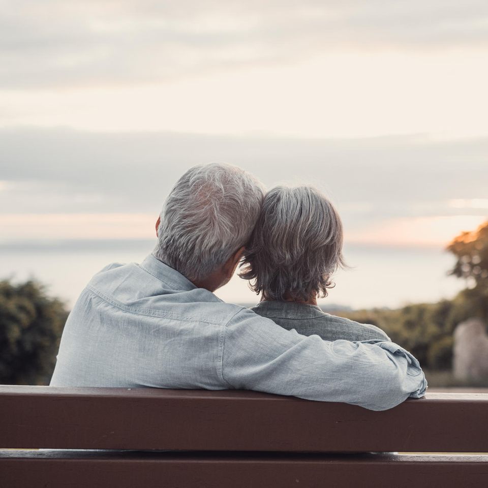 Ein älteres Paar sitzt auf einer Bank und umarmt sich