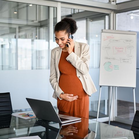 Schwangere Frau im Büro telefoniert