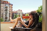 Wie sich 7 Erholungstypen von Stressphasen erholen: Frau liest ein Buch auf dem Balkon